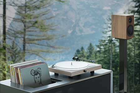 Platine vinyle et enceintes dans un décor forestier